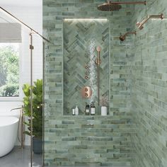 a bathroom with green tiles on the walls and floor, along with a white bathtub