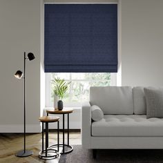 a living room with a couch, table and lamp in front of a window that has blue shades on it