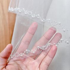 a person is holding their hand under a veil with beaded trimmings on it