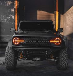 the front end of a black truck with its lights on