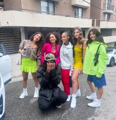 a group of young women standing next to each other in front of a parking lot