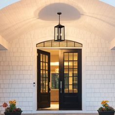 the front entrance to a home with two potted flowers on either side and an open door