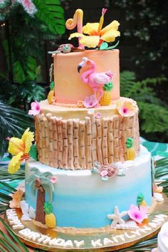 a three tiered cake decorated with palm trees and flamingos