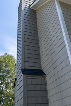 a tall building with a clock on the side of it's face next to trees