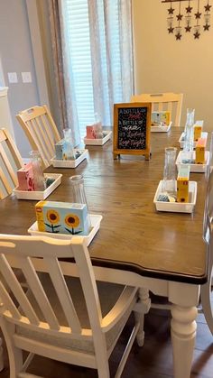 a dining room table with white chairs and a chalkboard