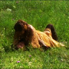 a person laying in the grass with their head on his back and one foot up