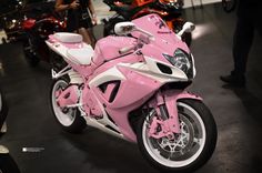 a pink and white motorcycle on display in a showroom