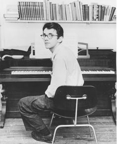 a man sitting at a piano in front of a bookshelf