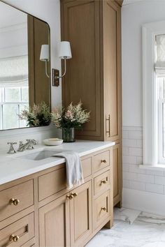 a bathroom with two sinks and large mirrors on the wall next to it's cabinets