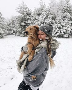 a woman holding a dog in the snow