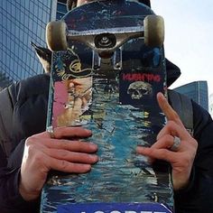 a man holding a skateboard in front of his face with graffiti on the board