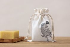 a small bag with a bird on it next to a bar of soap and a wooden block