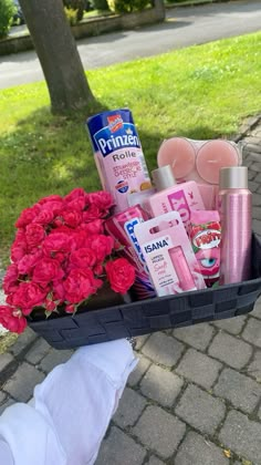 a person holding a basket filled with pink flowers and personal care products on the sidewalk