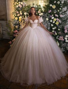 a woman in a ball gown standing next to flowers