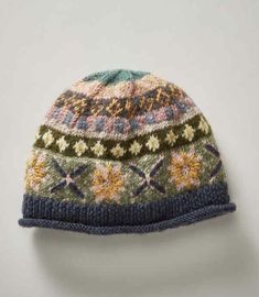 a knitted hat with flowers and leaves on the front, against a white background