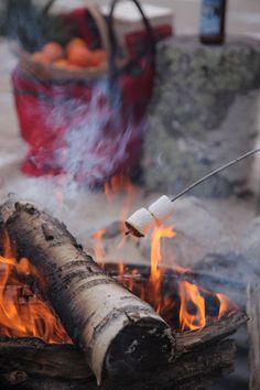 a person is cooking food over an open fire with marshmallows on it