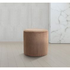 a round stool sitting on top of a hard wood floor next to a white wall