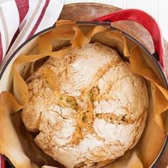 a loaf of bread sitting in a pot on top of a red and white table cloth