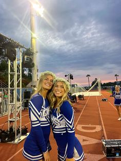 two cheerleaders pose for a photo on the field