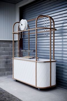 a white and gold cart sitting in front of a garage door with a clock on top