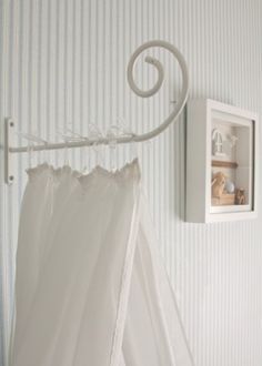 a white curtain hanging from a hook in a room with striped wall paper on the walls