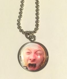 a necklace with an image of a man's face on it, hanging from a ball chain