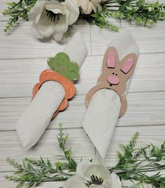 two napkins with bunny ears and carrots on them sitting next to white flowers