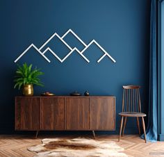 a blue room with a wooden sideboard, chair and plant on the floor in front of it