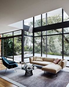 a living room with lots of windows and furniture in the center, along with an area rug on the floor