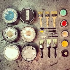 there are many paint cans and brushes on the ground