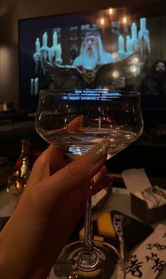 a person holding a wine glass in front of a television