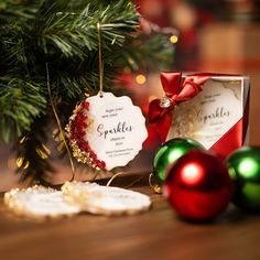 a christmas ornament next to two ornaments on a table with red and green baubles