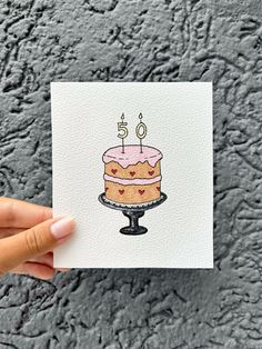 a hand holding up a card with a cake on it