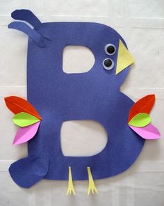 the letter b is made out of paper and decorated with colorful leaves, feathers and googly eyes