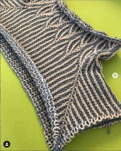 a knitted sweater laying on top of a green surface