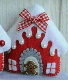 two red and white gingerbread house ornaments with a bow on the top one is made out of felt