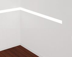 an empty room with white walls and wood flooring is seen in this image from the corner