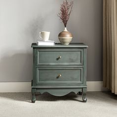 a green chest of drawers with a vase on top and coffee cup sitting on it