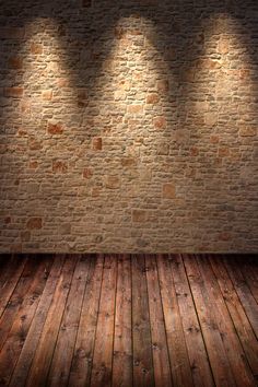 an empty room with three spotlights on the brick wall and wooden floor in front of it