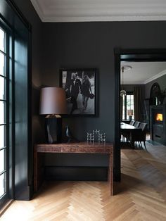 a living room with black walls and wooden floors, two pictures on the wall above a table