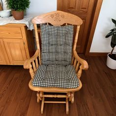 a wooden rocking chair sitting on top of a hard wood floor next to a potted plant