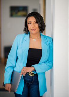 a woman in a blue blazer leaning against a wall