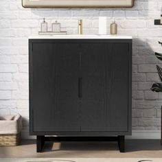 a bathroom with a white brick wall and a black cabinet next to a mirror on the wall