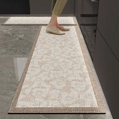 a person standing on top of a rug in the middle of a kitchen floor area