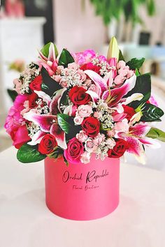 pink and red flowers in a pink box on a table