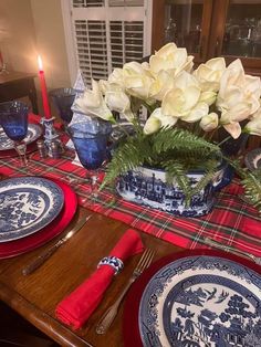 the table is set with blue and white plates, red napkins, and flowers