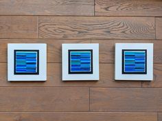 three square blue and white windows on a wooden wall