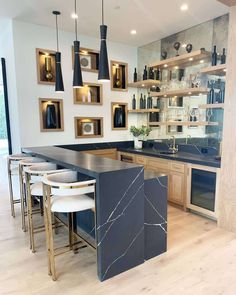 a modern kitchen with marble counter tops and wooden cabinets, along with hanging lights above the island