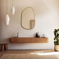 a mirror and some plants on a wall in a room with white walls, wood flooring and wooden furniture