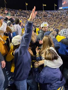 a group of people standing around each other at a football game with their hands in the air